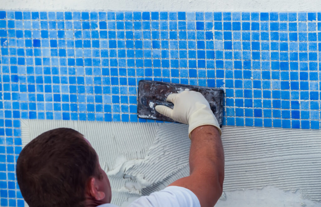 Worker-laying-tile-in-pool-repairing-work